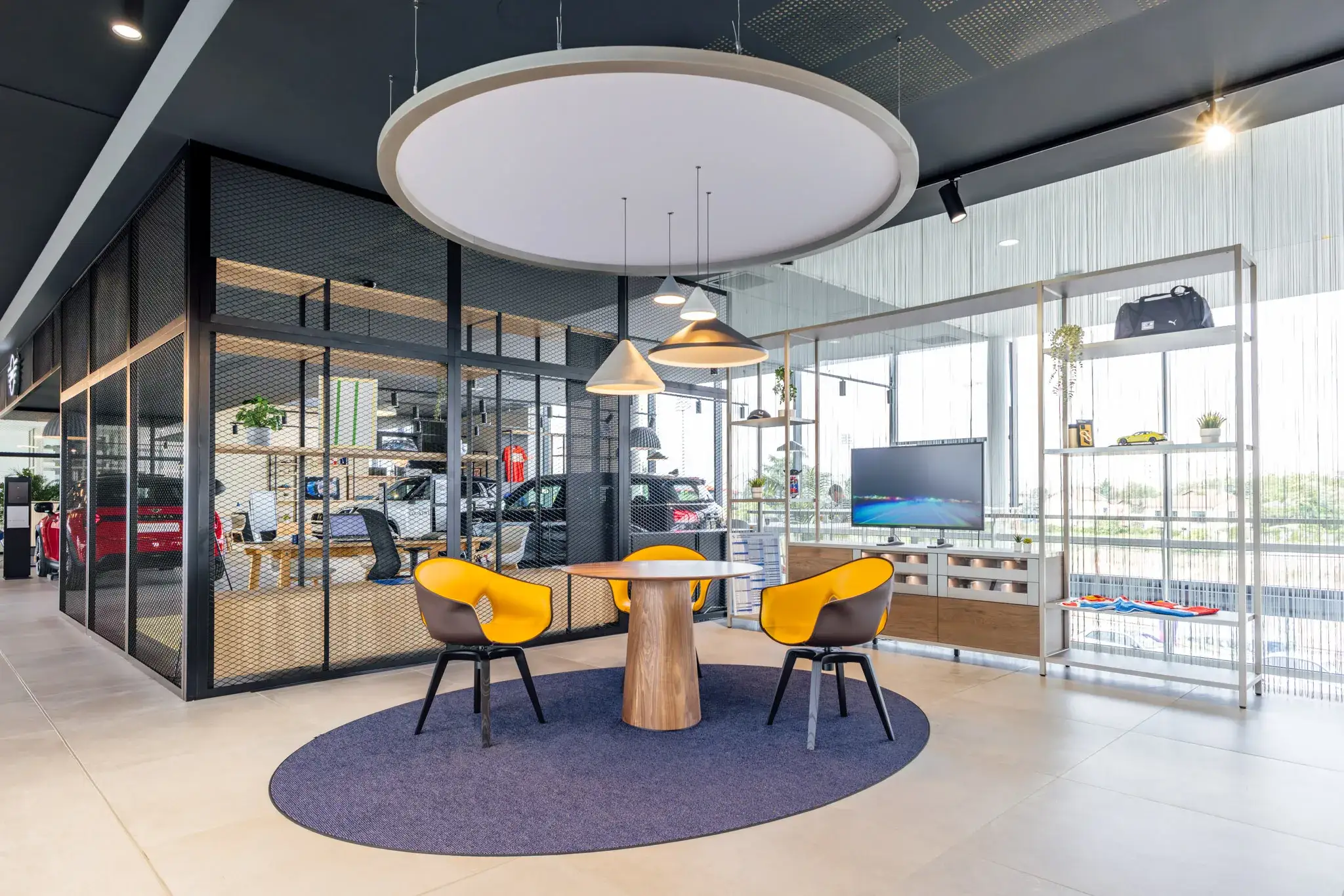 Espace de réunion moderne avec trois chaises jaunes autour d'une table ronde en bois dans un bureau lumineux