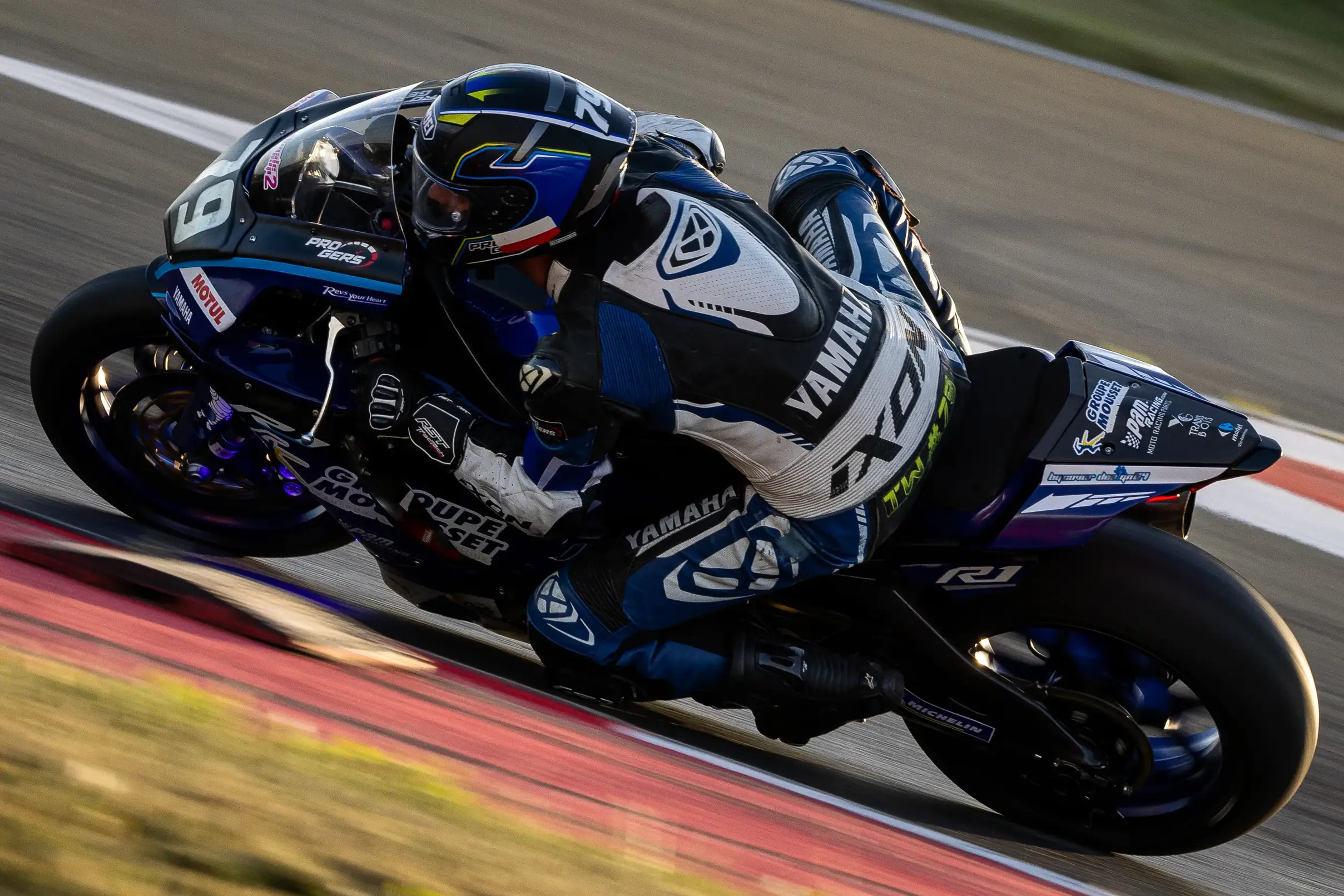 Pilote en combinaison Yamaha sur une moto de course noire sur un circuit en virage